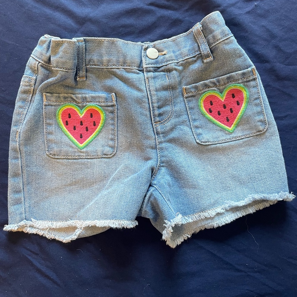 Light wash girls jean shorts. With watermelon heart designs on pockets